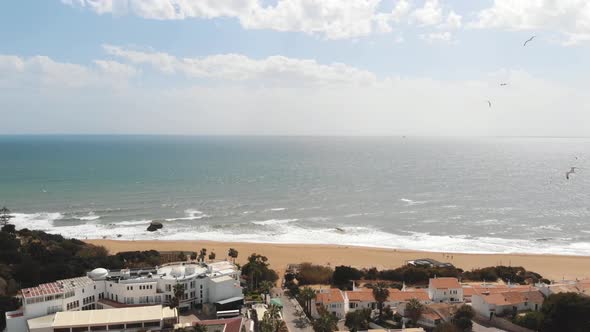 Panoramic scenic calm ocean shore with flying seagulls in Albufeira, Algarve - Pan aerial shot