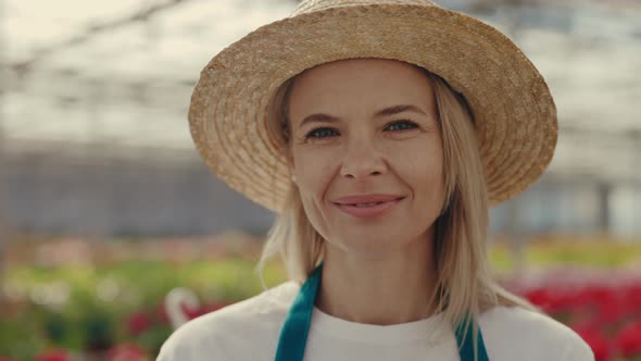 Portrait of the Female Gardener Looking and Smiling at the Camera Wearing Straw Hat