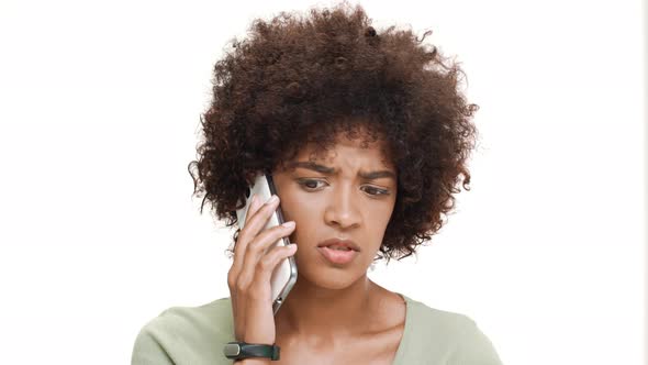 Upset Young Beautiful African Girl Speaking on Phone Over White Background