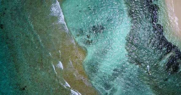 Wide angle fly over island view of a sunshine white sandy paradise beach and turquoise sea backgroun