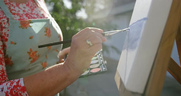 Senior woman painting on canvas in the garden 4k