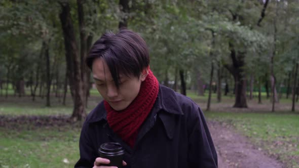 Young Asian Man Drinking Coffee in the Autumn Park