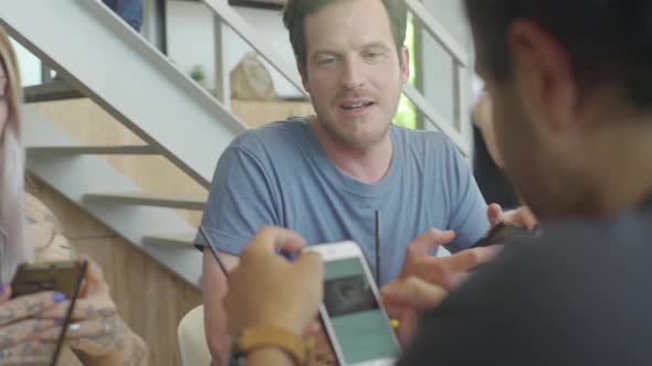 Friends hanging out together in cafe using smartphones