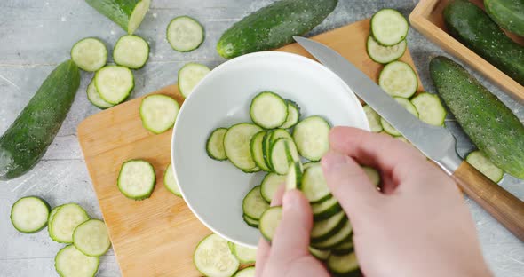 Men Hands Put Pieces of Sliced Cucumber in Bowl. 