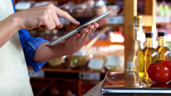 Female staff using digital tablet in supermarket