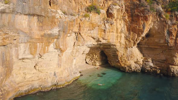A Couple of Travelers Swims in a Hidden Cove with a Cave in Mountain on the Road From Demre To