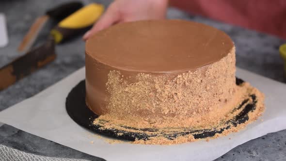 Female Hands Use the Crumbs To Decorate the Sides of the Cake