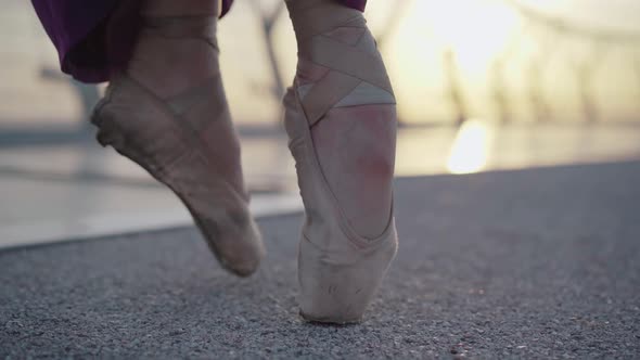 Close-up of Female Feet in Pointe Shoes Walking on Asphalt Bridge on Sunrise or Sunset