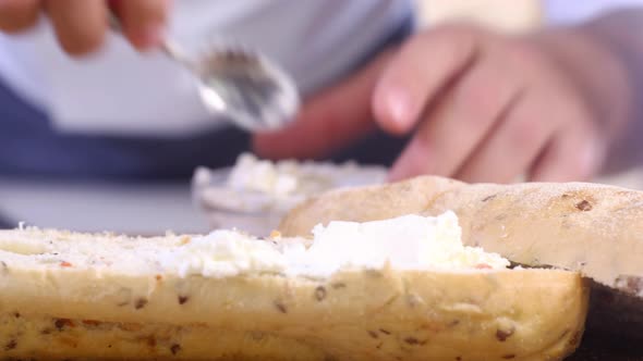 male chef spreads cream cheese on crunchy bun prepare sandwich