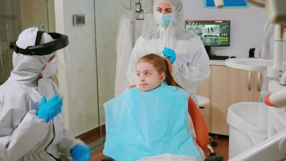 Little Girl with Dental Bib and Ppe Suit Listening Pediatric Dentist in Coverall