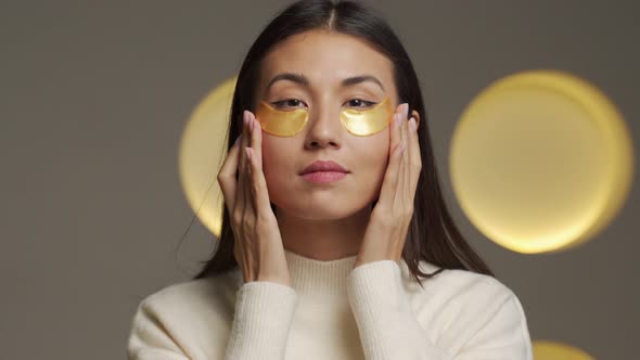 Young Asian Woman with Clear Radiant Skin with Moisturizing Golden Patches Under Her Eyes