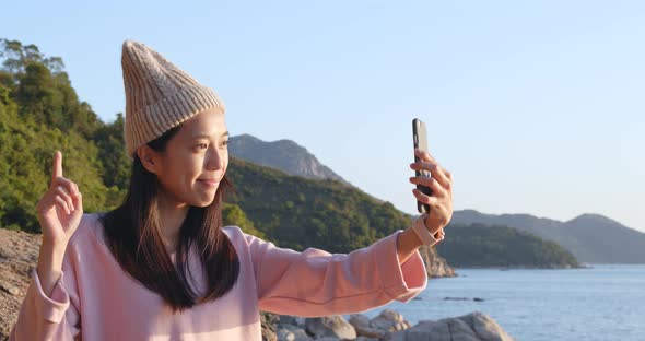 Woman taking video call on cellphone over seascape