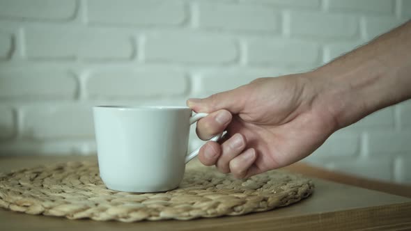 Put and take a white cup of green tea on a wooden table