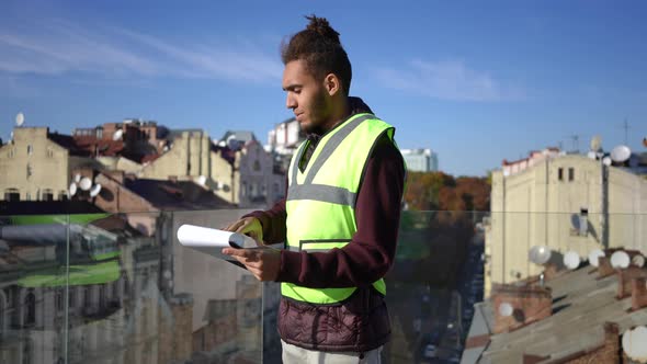 Young Intelligent African American Man Analyzing Project Standing on Urban Rooftop in Sunshine