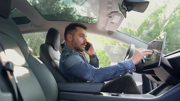 Modern Man Sitting at Helm of His Expensive Car, Talking on Mobile and Using gps Navigator