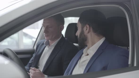 Side View of Wealthy Middle Eastern Man Talking with Dealer in Car. Close-up of Successful Man