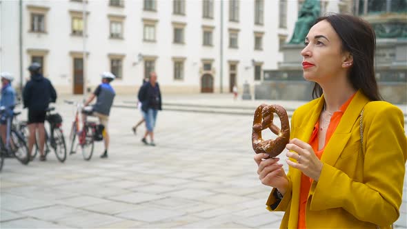 Beautiful Young Woman Holding Pretzel and Relaxing in Park