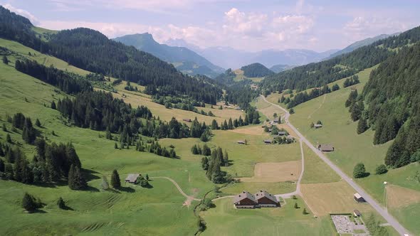 Aerial View of a Valley in Switzerland with Chalets and a Mountainous Landscape