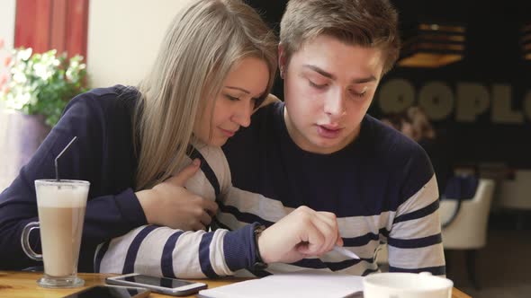 Young Man Writing a Letter or Doing His Homework in a Cafe