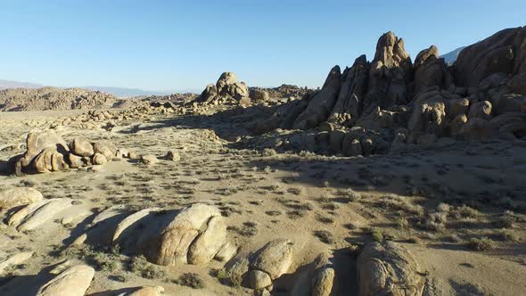 Aerial shot of a young man backpacker standing on a boulder with his dog in a desert mountain range.