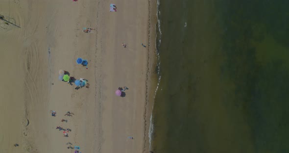 Top Down Aerial Pan of People Relaxing on the Sandy Beach Shore of Long Island