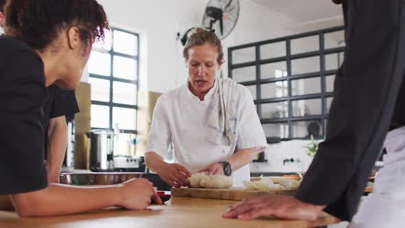 Caucasian female chef teaching diverse group wearing face masks