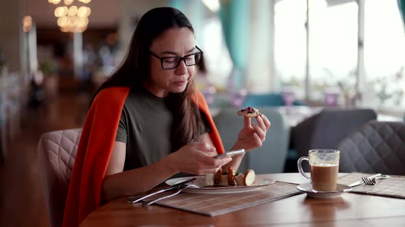 A Pretty Adult Woman Writes a Message on Her Mobile Phone Enjoying a Conversation Having Breakfast