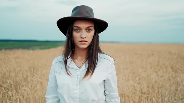 Beautiful Girl in a Shorts and Hat Walking Through a Wheat Field at Sunset. Freedom Concept. Wheat