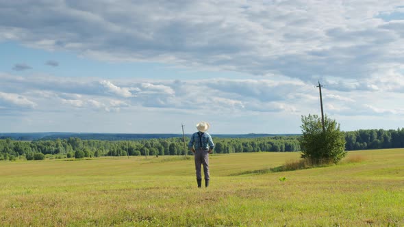 Farmer Standing in Mown Field Looking Far Ahead