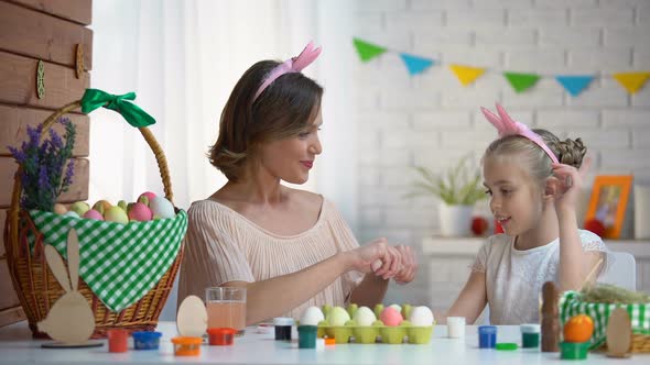 Cheerful Mother and Daughter Preparing for Easter Playing With Decorated Eggs