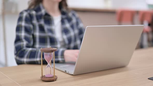 Woman Feeling Disappointed Next To Laptop and Hourglass