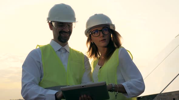 Female and Male Solar Inspectors Working Near Solar Panels