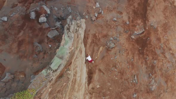 Man Climbing Rocky Mountain at Capelinhos Volcano Faial Island Azores