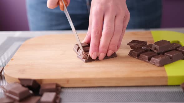 Woman Chopping Black Dark Chocolate on Wooden Cutting Board