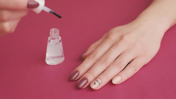 Woman is Applying Top Coat on Gel Polish Nails for Herself