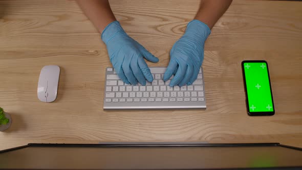 Woman's Hands in Protective Blue Gloves Who Types on the Keyboard in the Office or at Home