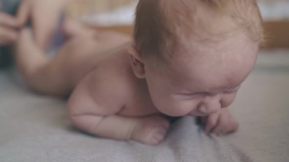 Baby with Blond Hair Lies on Stomach on Changing Table