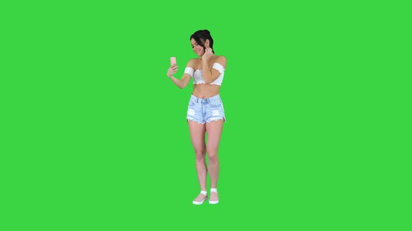 Beautiful Young Woman Doing Selfie on a Green Screen, Chroma Key.