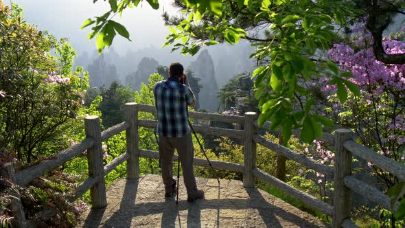 Landscape Photographer with Tripod and Camera Taking Pictures of Beautiful Mountains at Sunset