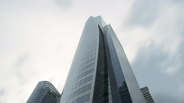 Glass skyscraper of modern design at the clouds background
