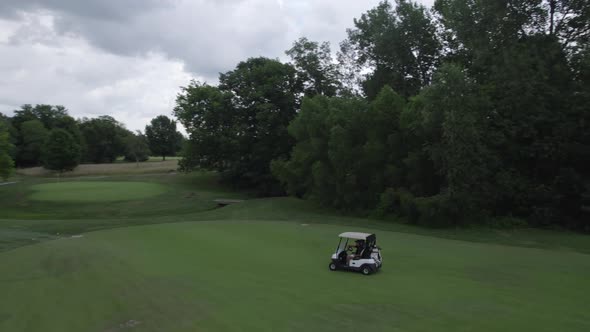 following golf carts driving on golf course, aerial drone