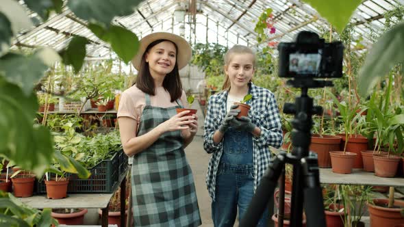 Young Woman and Child Farmers Recording Video Talking Showing Thumbsup in Greenhouse Using Camera