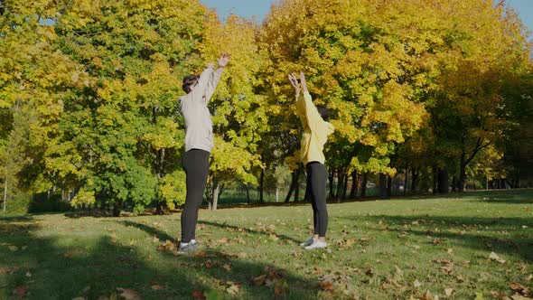 Man and Woman Doing Breathing Exercises at the Park in the Autumn Morning