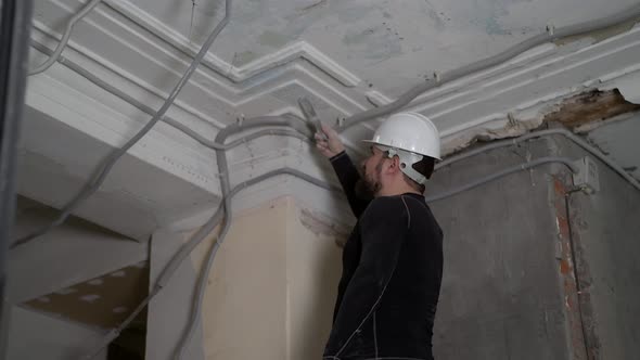 Fat Bearded Adult Man in Protective Helmet and Black Tight Fitting Clothing Remove Construction