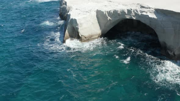 Aerial View of Sarakiniko Lunar Volcanic Beach with Waves Crashing Into Rocks in Milos, Greece