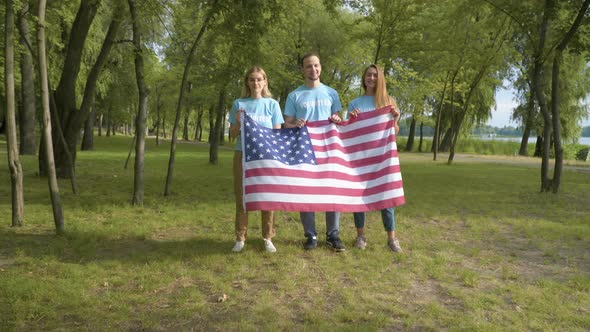 Group of Smiling Volunteers Posing with American Flag on Sunny Day After Cleaning Park, Portrait 