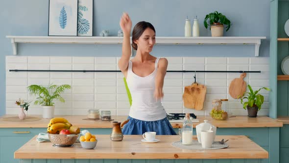 Young Joyful Woman Dancing Behind The Kitchen Table