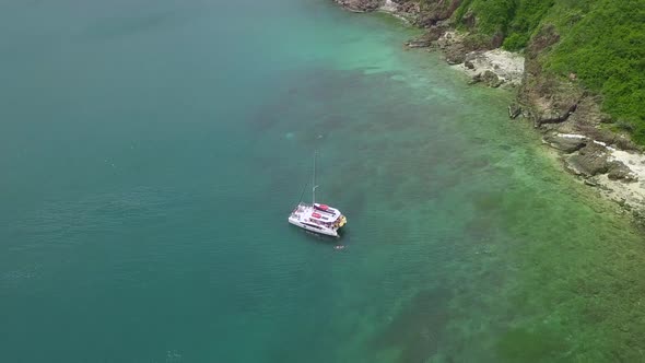 Man Swims Near Yacht Drifting on Tranquil Azure Sea By Coast