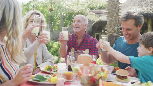 Happy caucasian family having dinner and talking in garden