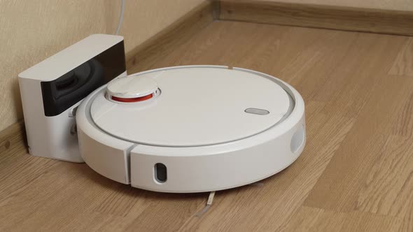 White Robotic Vacuum Cleaner Starts Cleaning From Its Charging Station